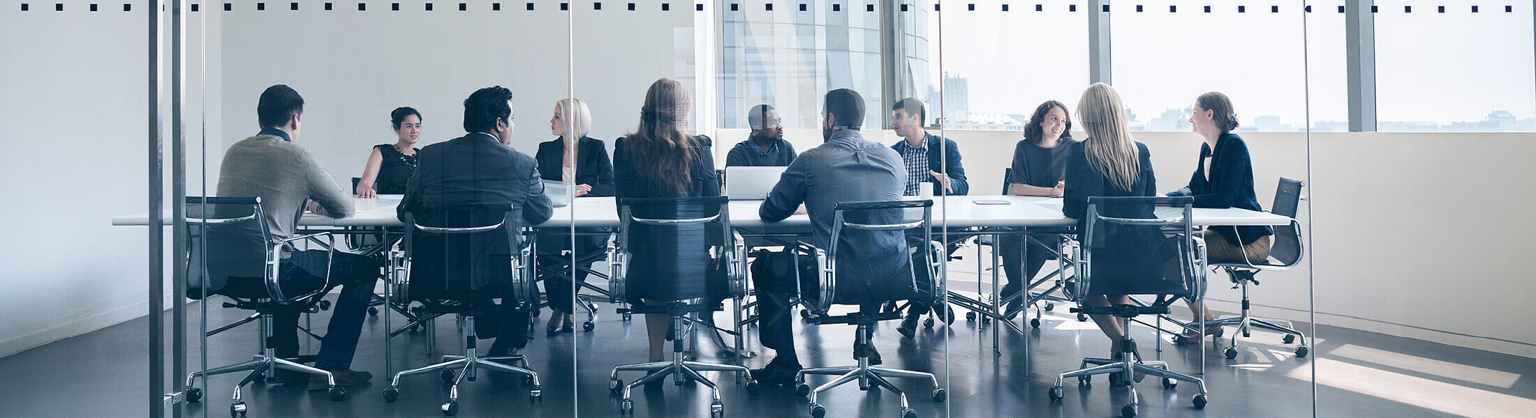 Eine Gruppe von Menschen im gläsernen Besprechungsraum